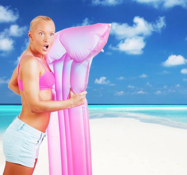 Emotional blond woman posing with pink water matress on white background