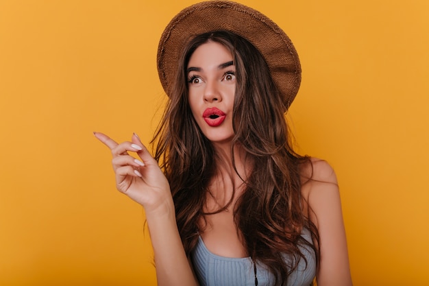 Emotional brown-haired girl with long nails standing on yellow space