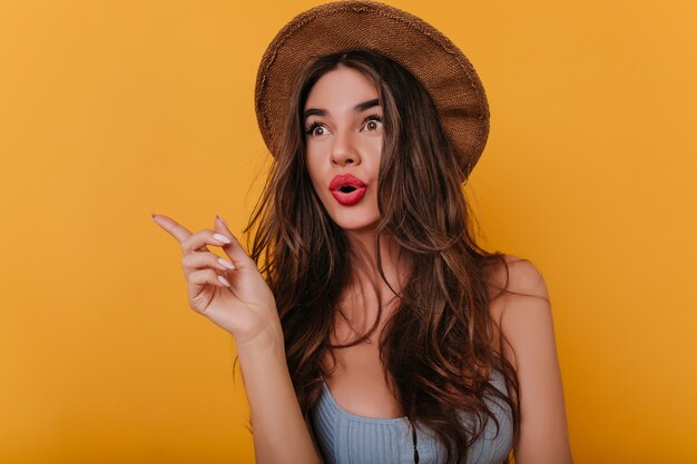 Emotional brown-haired girl with long nails standing on yellow space