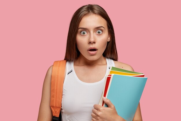 Emotional European woman with dark hair, has stupefied expression, hears unexpected news