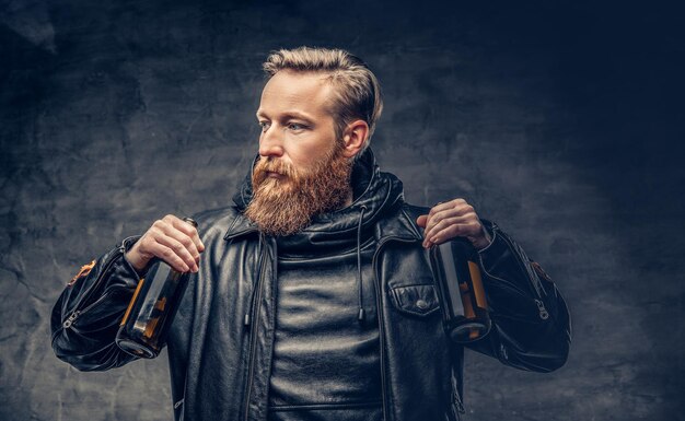 Emotional, funny redhead bearded drunk hipster male holds craft bottled beer.