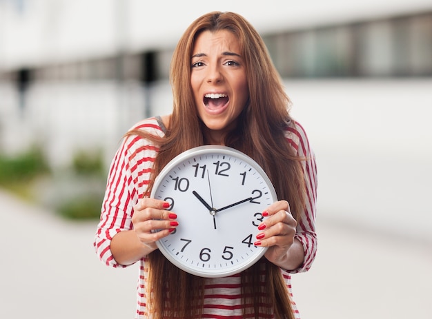 Emotional girl holding big clock