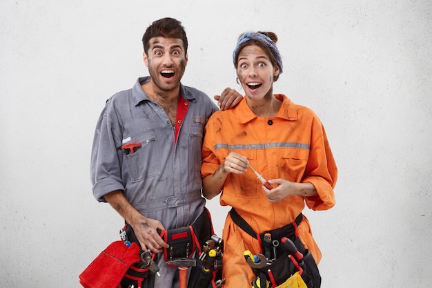 Free photo emotional happy female and male carpenters look with excitement or surprisment