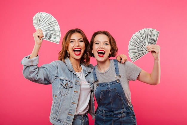 Emotional pretty two women friends holding money