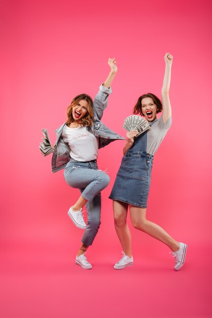 Emotional pretty two women friends holding money