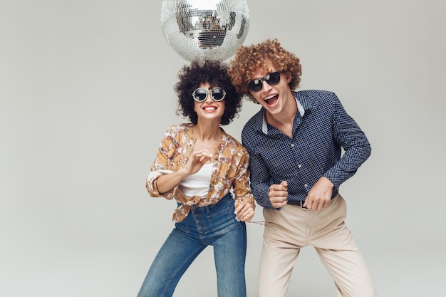 Foto gratuita retro coppie amorose sorridenti emotive che ballano vicino alla palla della discoteca.