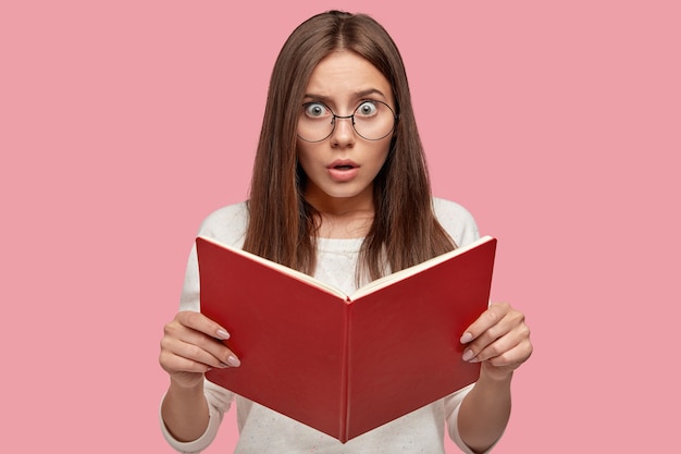 Emotional surprised young woman wears round spectacles