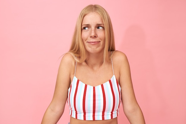 emotional timid European woman in stylish striped top shrugging shoulders