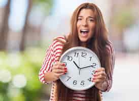Free photo emotional woman screaming and holding clock