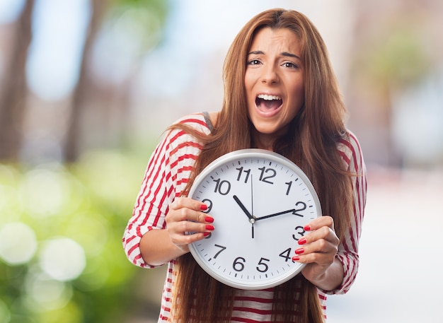 Emotional woman screaming and holding clock