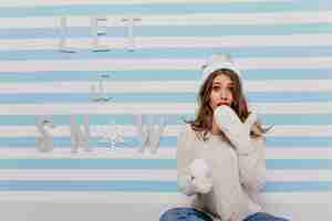 Foto gratuita donna emotiva in cappello bianco lavorato a maglia sopra iscrizione invernale: let it snow