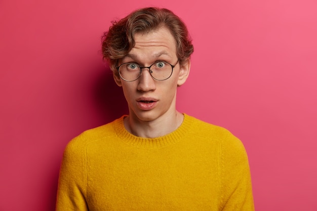 Free photo emotional wondered male student finds out bad results of passed exam, cannot believe in failure, feels surprised hearing interesting rumor, gazes impressed , wears spectacles, yellow sweater