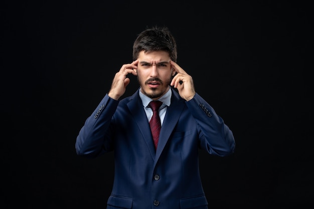 Emotional and young bearded man concentrated on something on isolated dark wall