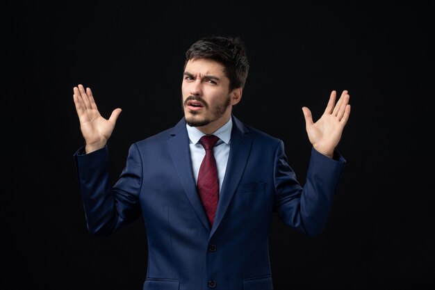 Emotional and young bearded man posing with bewildered facial expression on isolated dark wall