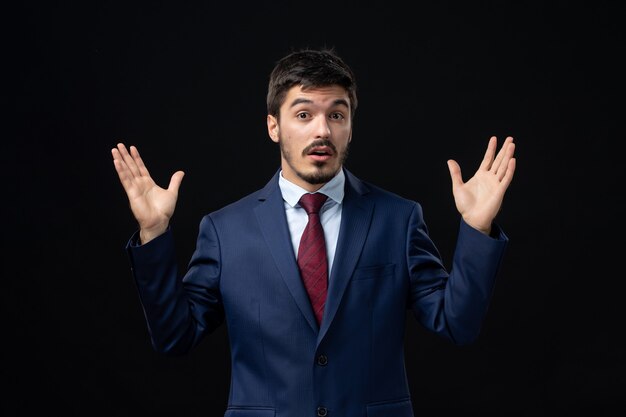 Emotional and young bearded man posing with confused facial expression on isolated dark wall