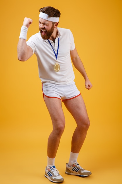 Emotional young sportsman with medal make winner gesture.