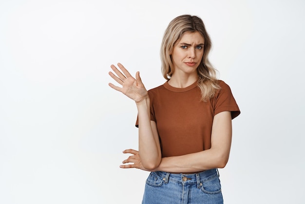 Emotions and gestures Picky and skeptical blond woman say no wave hand in refusal gest rejecting something with reluctance standing over white background