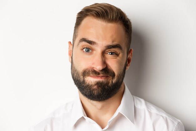 Emotions and people concept. Headshot of skeptical man with beard, grimacing and looking doubtful, standing displeased