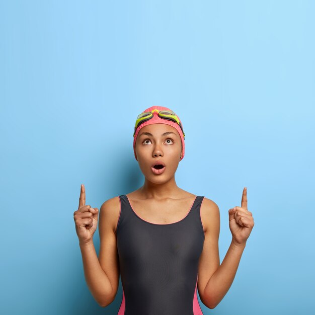 Emotive athletic woman in black swimsuit and bathing cap