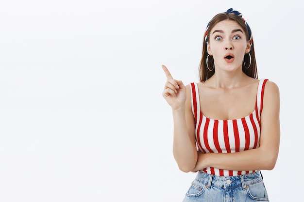 Free photo emotive enthusiastic attractive young woman in striped pin-up top and headband raising index finger in eureka gesture gasping and smiling excited, adding idea