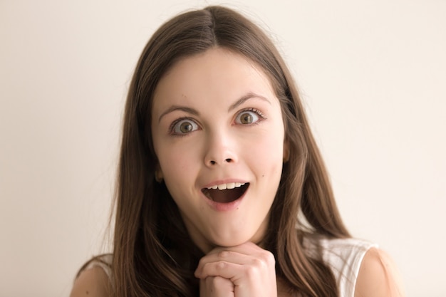 Emotive headshot portrait of amazed young woman