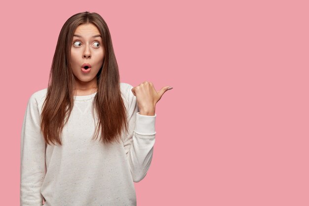 Emotive terrified beautiful brunette posing against the pink wall