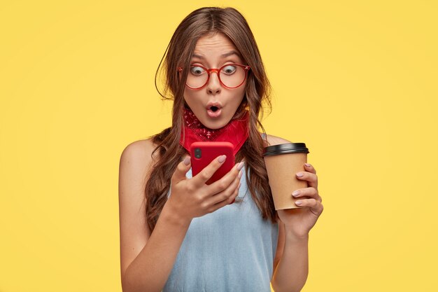 Emotive young brunette with glasses posing against the yellow wall