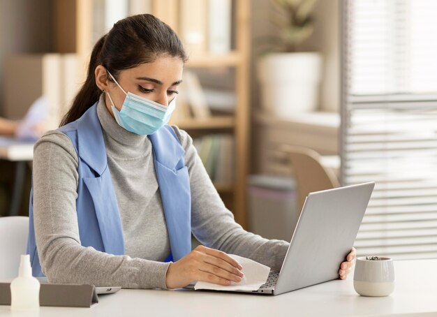 employee disinfecting electronic device