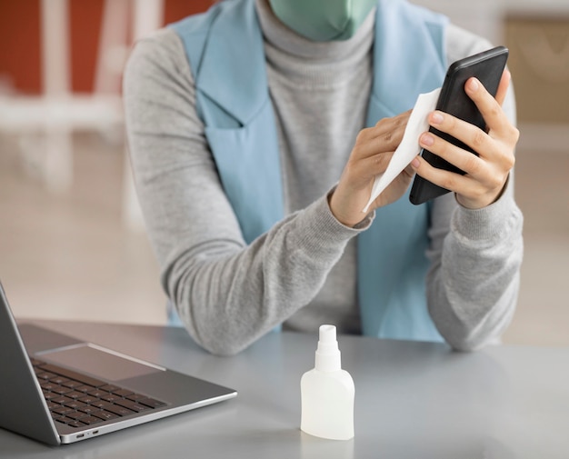 Employee disinfecting electronic device