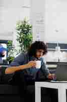 Free photo employee drinking coffee and reading customer email on laptop