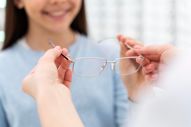 Employee helping girl to try on glasses