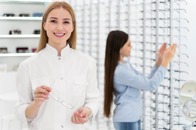 Free photo employee helping girl to try on glasses