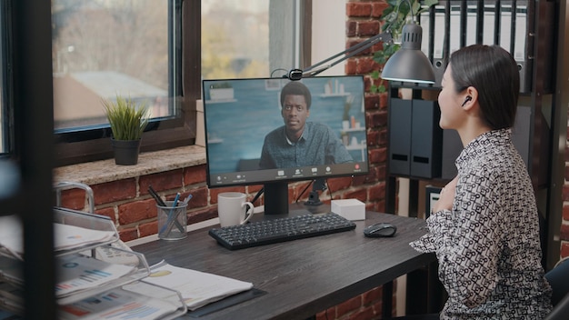 Employee talking to man on video call communication in startup office. Business woman using remote video conference to have conversation about project planning with colleague. Online meeting