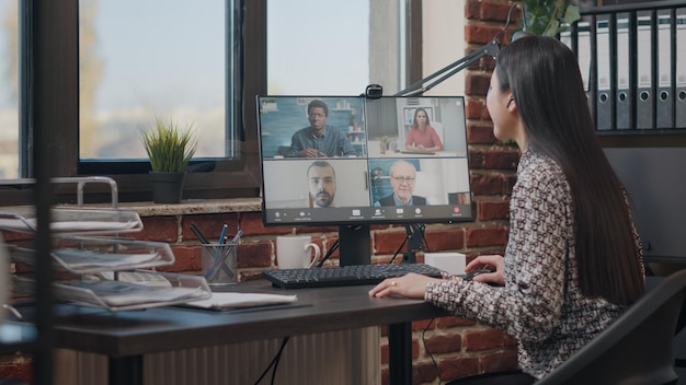 Employee talking to workmates on online video call, meeting to discuss business project. Woman using remote teleconference on computer with colleagues. Video conference on webcam