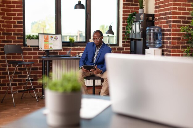 Employee using digital tablet to work on marketing strategy at workplace. Business man working on internet with gadget to plan financial project, brainstorming ideas for startup company.