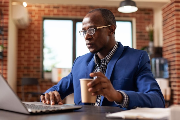 Employee using laptop to work on project planning and strategy at office job. Business man working with computer on financial paperwork and surfing internet at desk. Focused employee