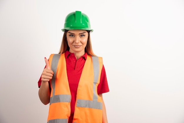 Employee woman in a vest and protective helmet on white background.