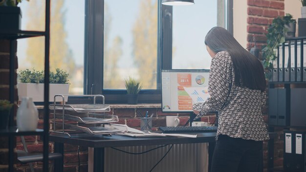 Employee working on project planning with files and data charts on computer in startup office. Business woman using papers to design strategy for management and leadership. Job development