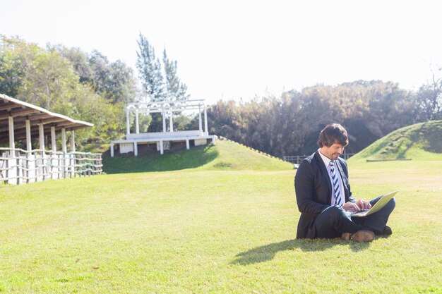 Employee working with his laptop sitting on the grass