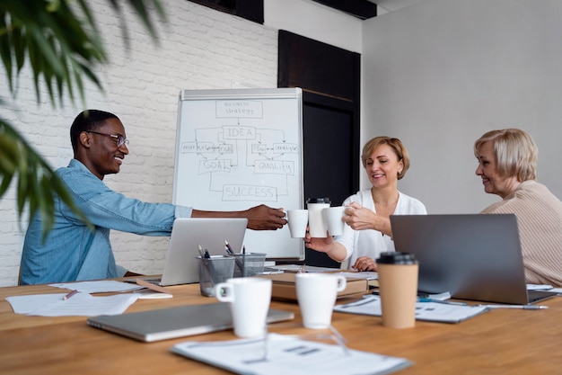 Employees in business meeting clinking cups