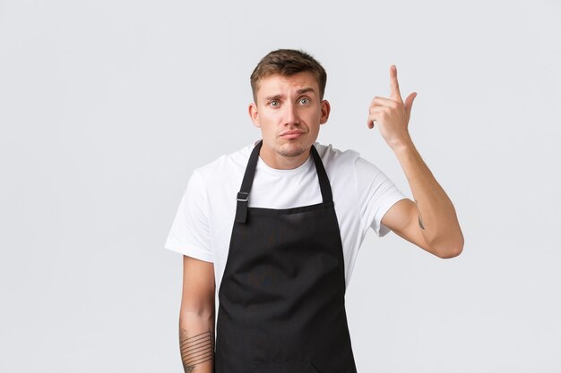 Employees, grocery stores and coffee shop concept. Annoyed and concerned barista, cafe manager scolding waiter for making stupid mistake, point at temple, accusing someone crazy