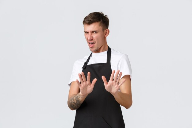 Employees, grocery stores and coffee shop concept. Displeased and reluctant picky guy step back and extend hands in stop sign, refusing and rejecting awful disgusting drink, white background