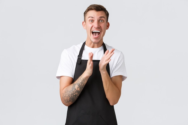 Free photo employees, grocery stores and coffee shop concept. happy impressed and excited barista in black apron clap hands for masterclass on brewing coffee, applause over white background