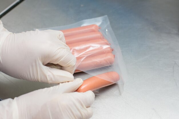 Employees sorting produced meat sausages