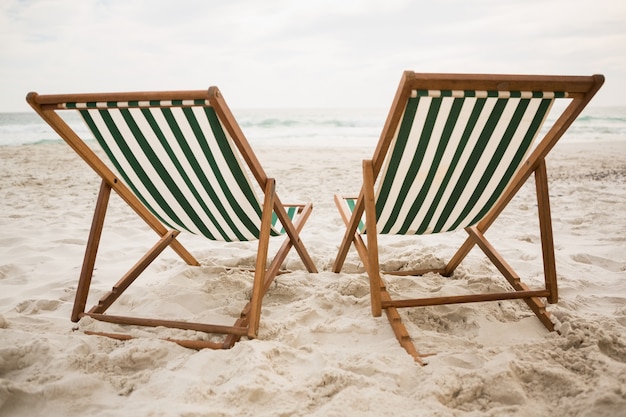 Foto gratuita sedie a sdraio vuote sulla spiaggia di sabbia tropicale