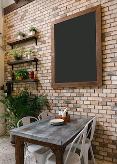 벽돌 벽 및 식사 테이블에 빈 블랙 보드 아래.