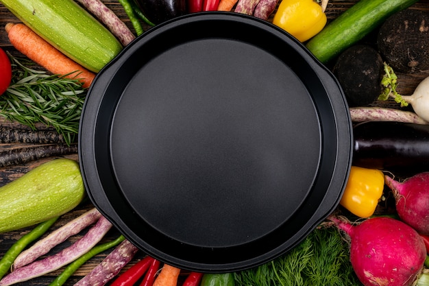 Empty black pan with fresh vegetables around