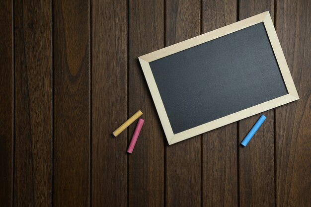 empty blackboard with chalks on vintage wooden background