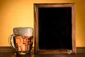 Free photo empty blackboard with glass of beer on wooden table