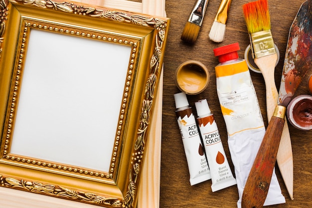Empty canvas in golden frame and paint brushes